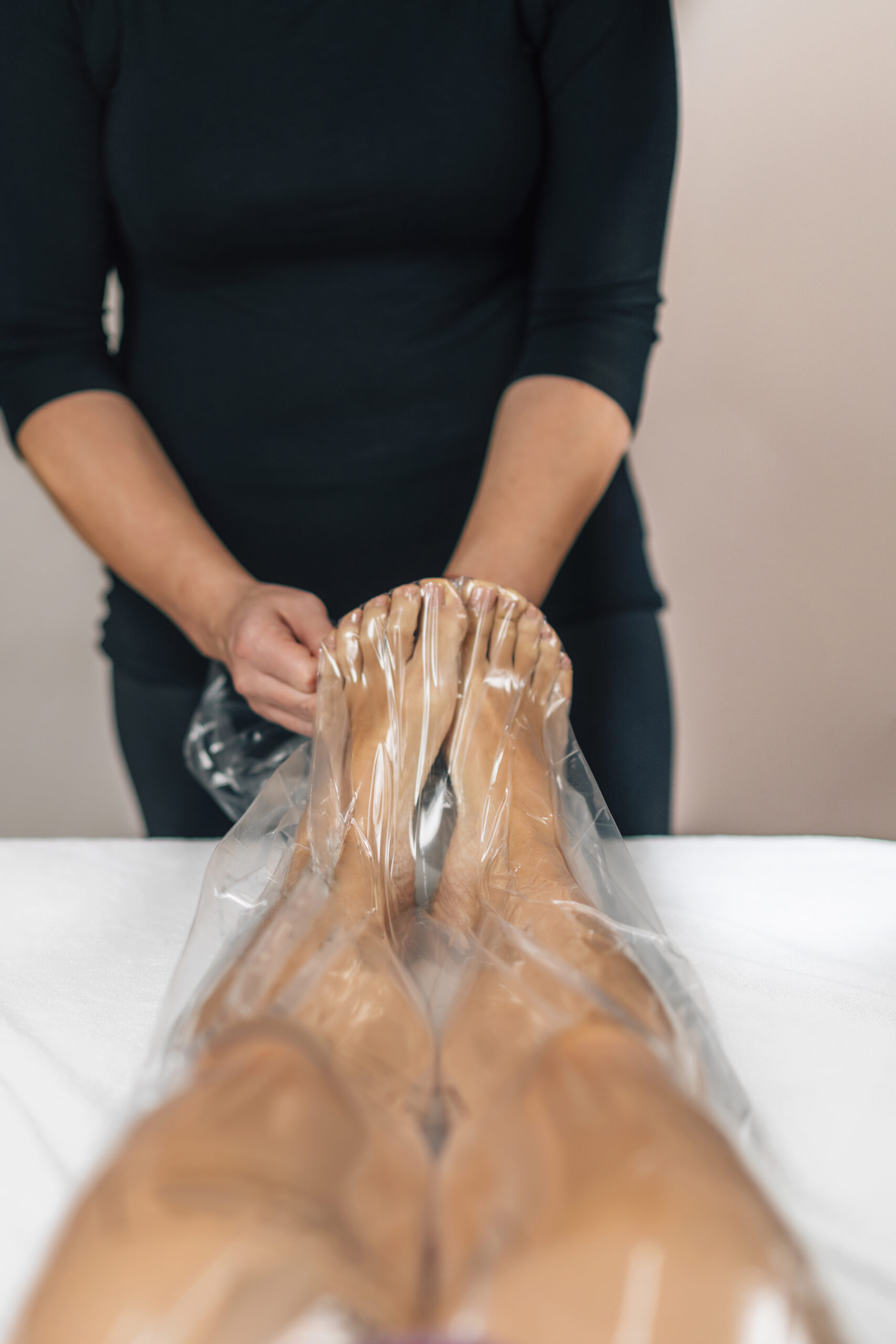 Anti-cellulite vacuum slimming treatment with a nylon bag for legs. Female client lying on a massage table in a beauty wellness center.